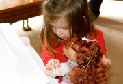 Maddie showing her new doll how to play her piano from Papa.